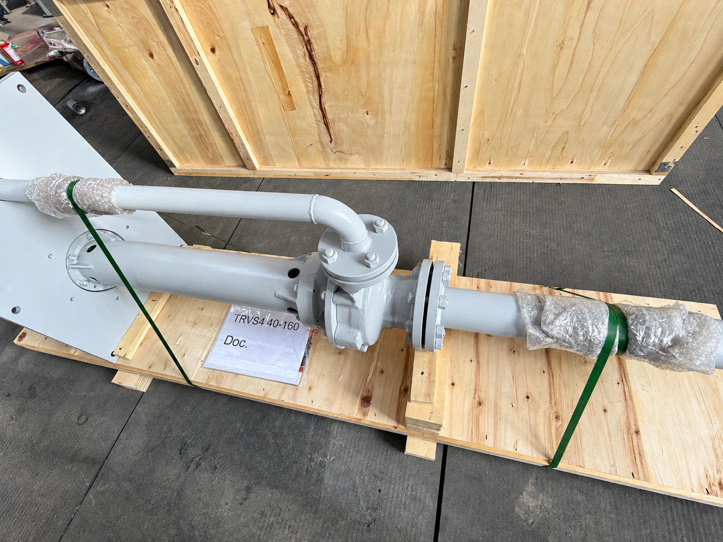 Close view of the pump column and separate discharge pipe on wooden supports.