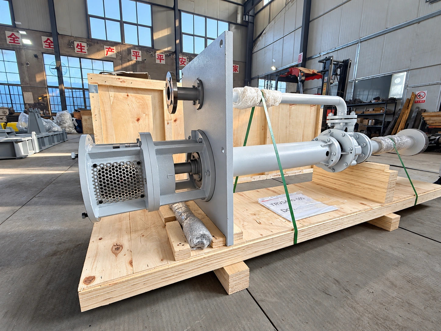 Grey long-column pump and pipework on a workshop pallet.